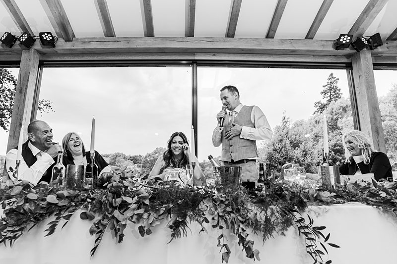 Wedding speech laughter at decorated banquet table.