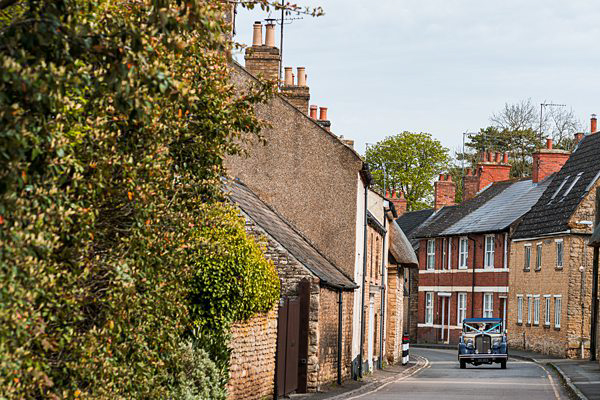 Quaint UK village street with vintage car.