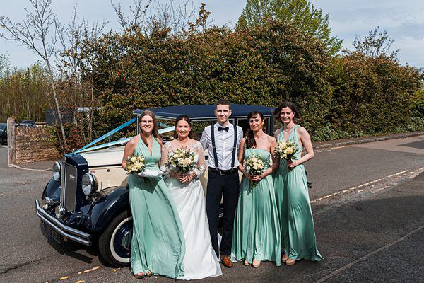 Bride, groom and bridesmaids with vintage car.