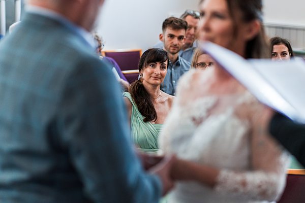 Wedding guests watching bride and groom exchanging vows.
