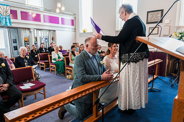 Wedding ceremony in a church with guests watching.