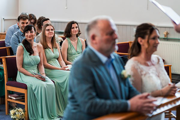 Wedding guests seated in church ceremony.