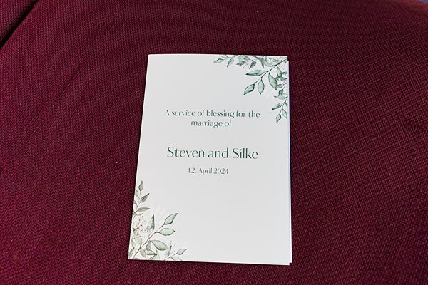 Wedding program for Steven and Silke on burgundy fabric.