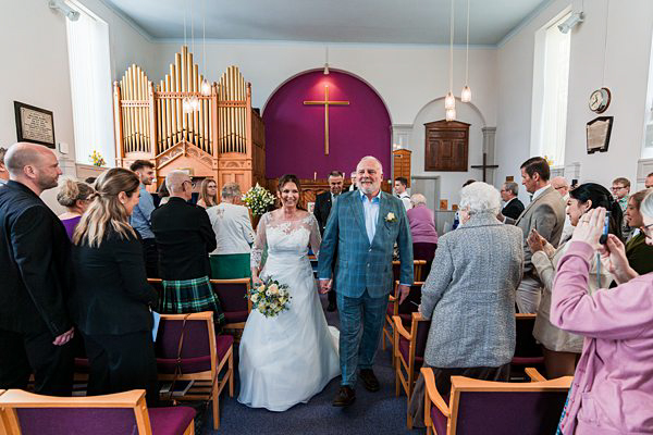 Bride and groom smiling in church wedding ceremony.