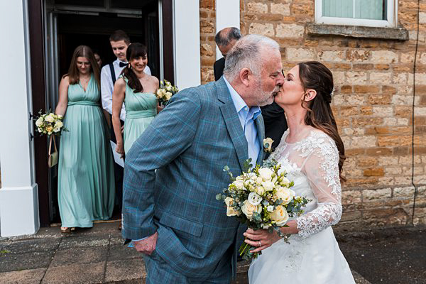 Bride kissing her husband outside wedding venue.