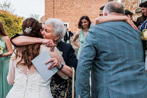 Elderly woman embracing bride at wedding ceremony.