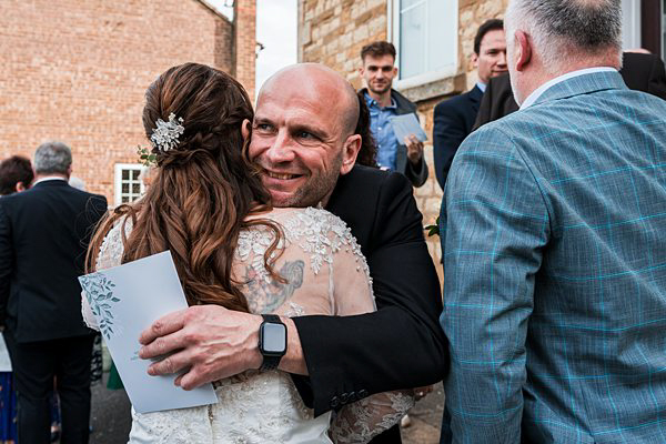 Bride and guest hugging at wedding reception.