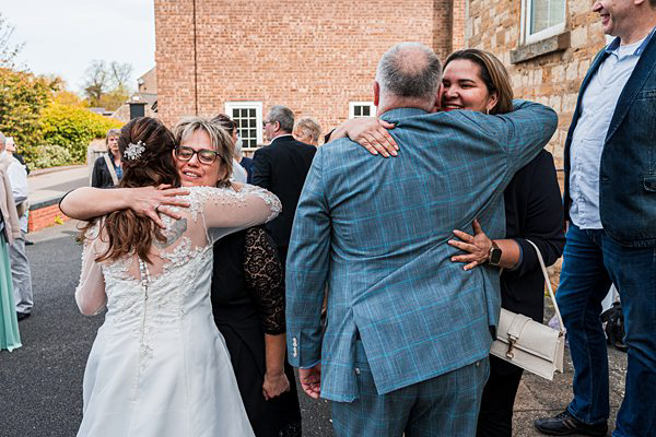Wedding guests hugging joyfully outdoors.