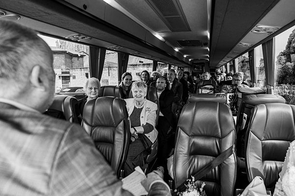 Passengers seated inside a coach bus, black and white photo.