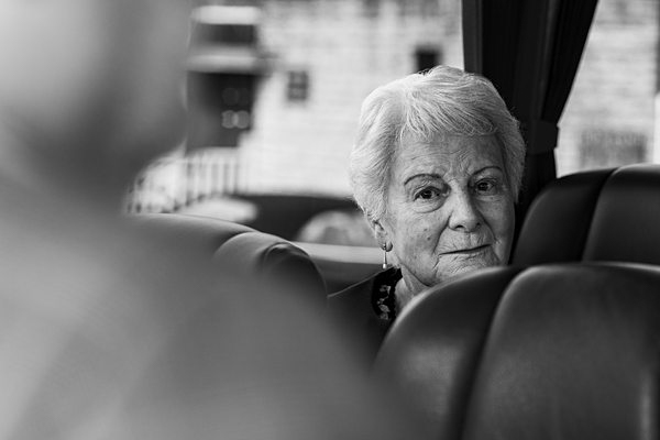 Elderly woman sitting inside bus, black and white photo.