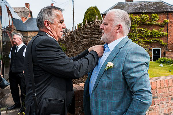 Two men adjusting attire at outdoor event.