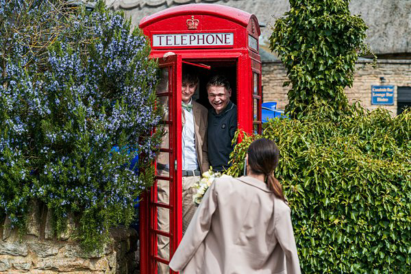 Two people smiling inside red British phone box.