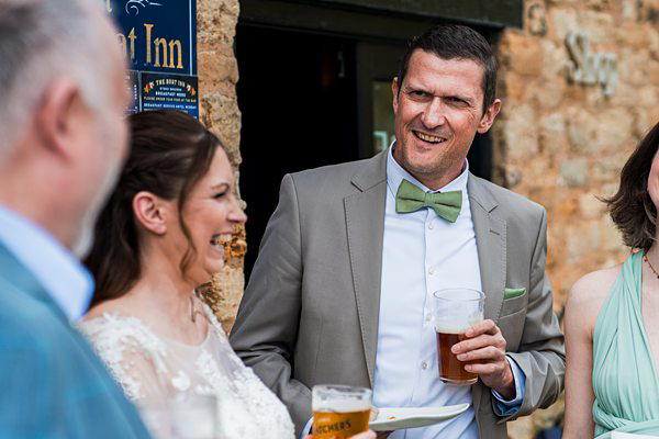Wedding guests laughing outside a rustic inn.