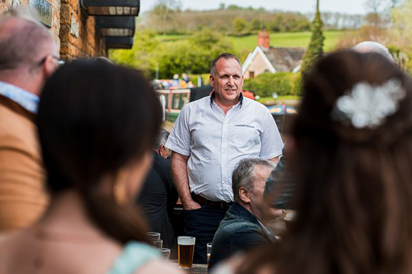 Man speaking at outdoor gathering in UK.