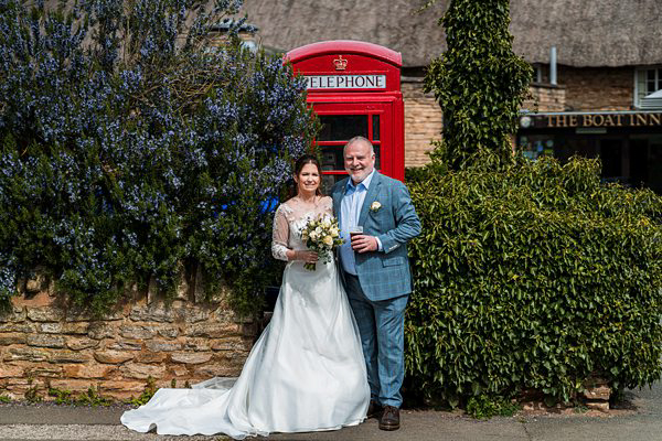 Couple posing by red telephone box outside British pub.