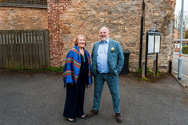 Couple standing together near historic building entrance.