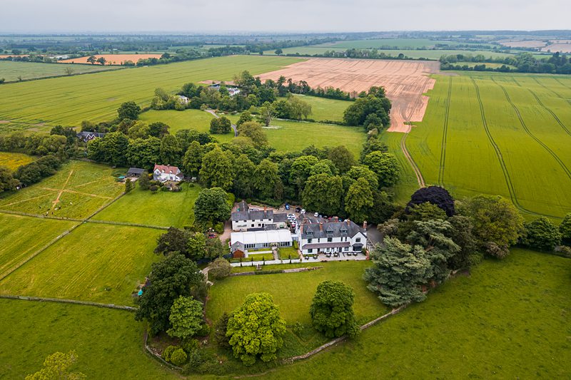 Aerial view of countryside estate surrounded by green fields.