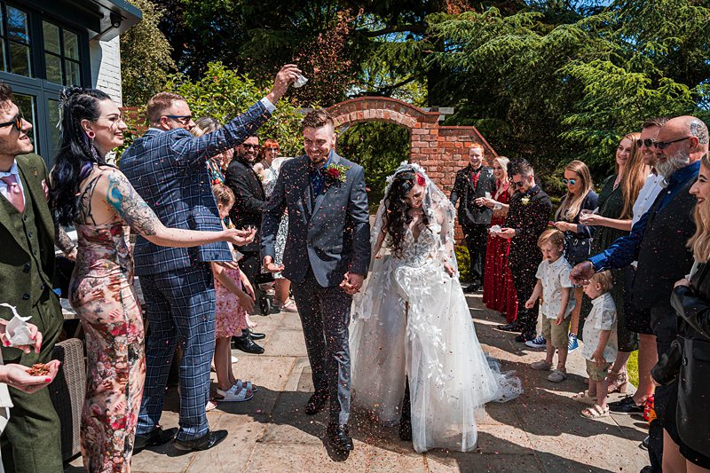 Couple exits wedding ceremony, guests throwing confetti.