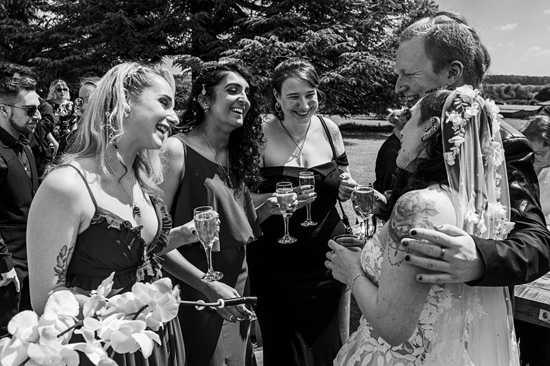 Wedding guests laughing and drinking with the bride and groom.