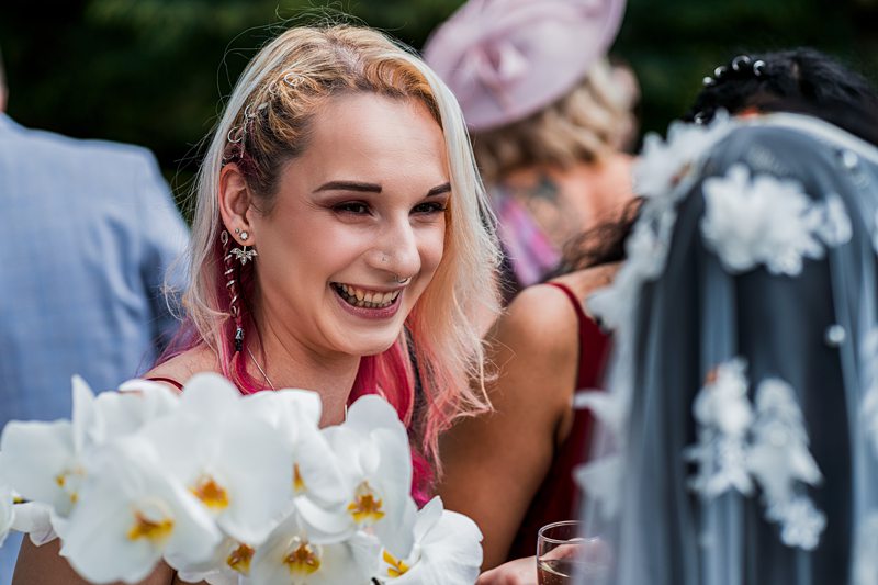 Smiling person at outdoor event holding white flowers.