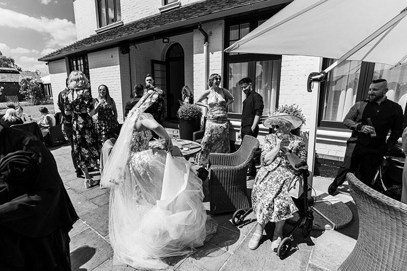 Wedding reception with guests mingling outside under an umbrella.