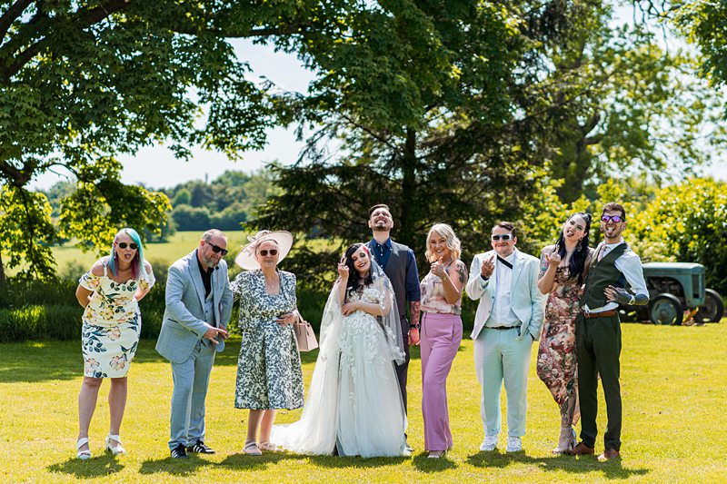 Wedding group photo outdoors on a sunny day.