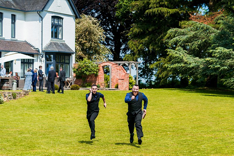 Two men running on grass towards camera at event.