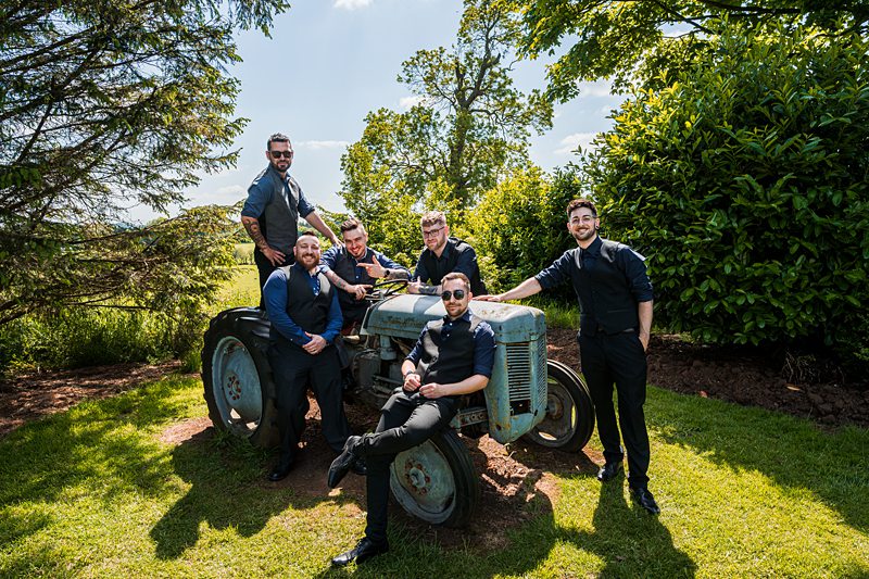 Men posing around vintage tractor in garden.