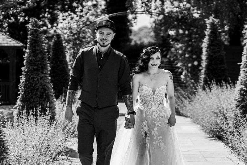 Bride and groom walking in garden.
