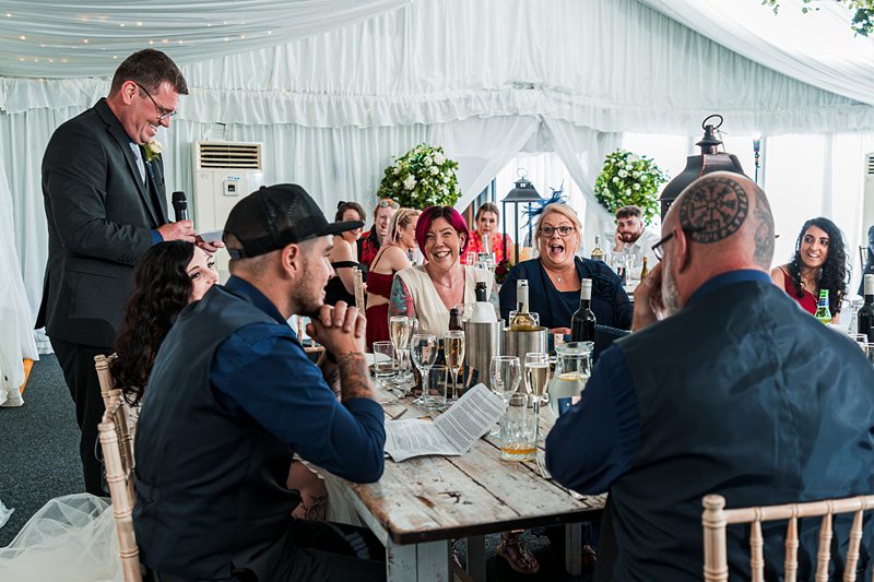 Wedding speech with smiling guests at reception.