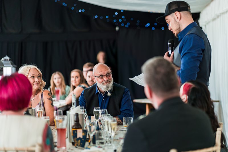 Man giving speech at wedding reception.