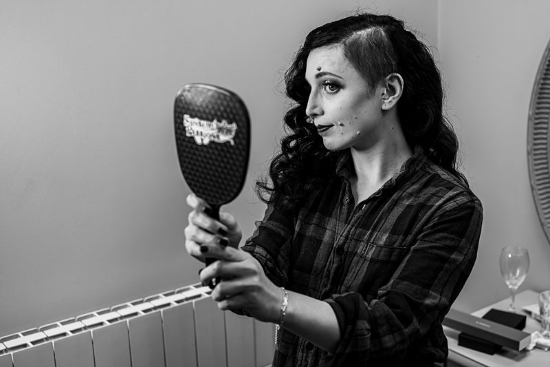 Person holding a mirror and styling hair in bedroom.