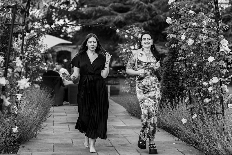 Two women walking through a flower garden.