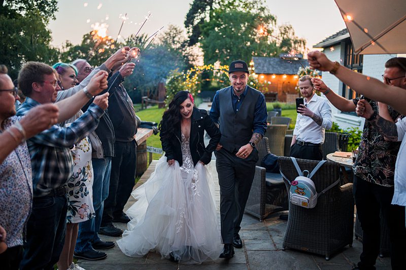 Bride and groom joyfully entering surrounded by sparklers.