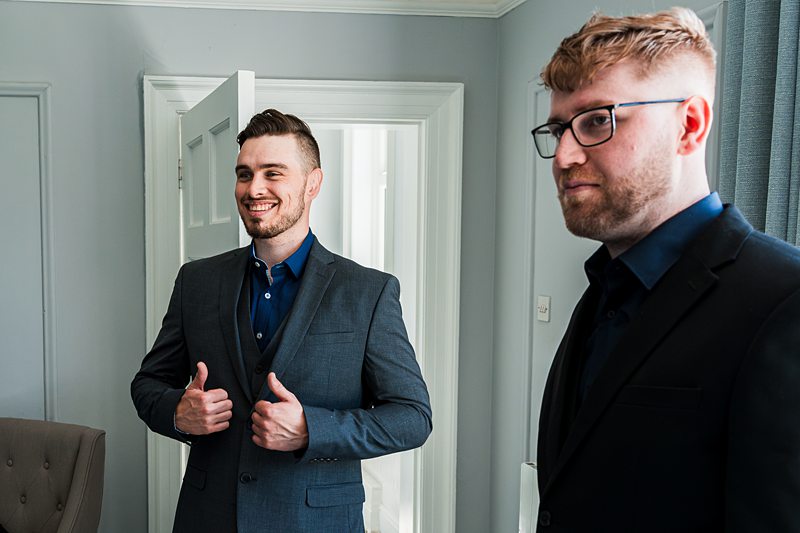 Two men in suits preparing for an event.