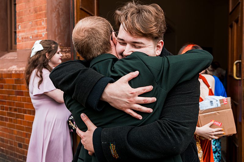 Two friends hugging outside a building.