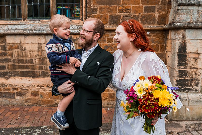 Wedding couple with child and flowers outside church