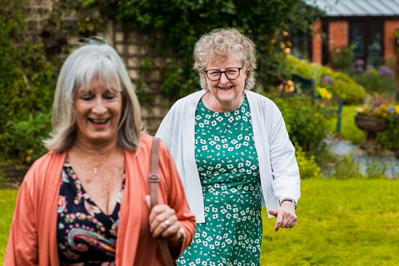 Two elderly women smiling in a garden