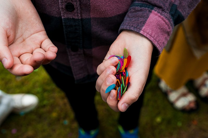 Child holding colourful confetti in hand.