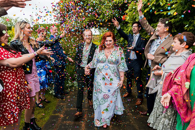Couple celebrates wedding with confetti and friends.