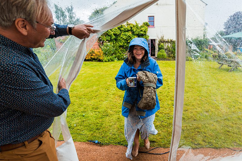 Woman in raincoat greeted at tent opening