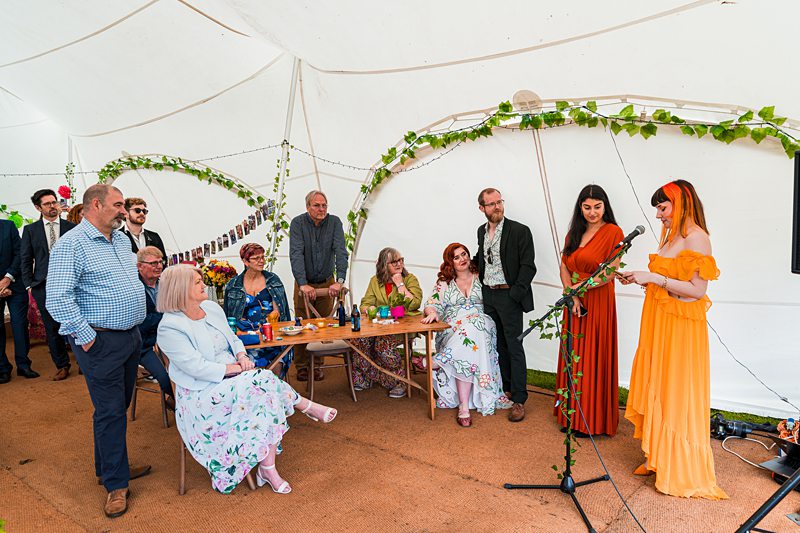 People at a wedding ceremony inside a decorated tent.