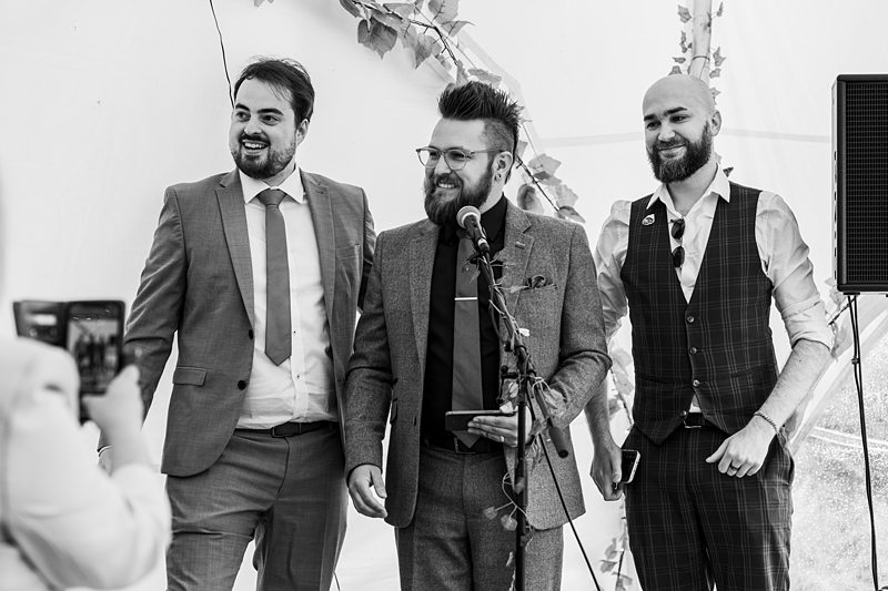 Three men giving a speech at a wedding.