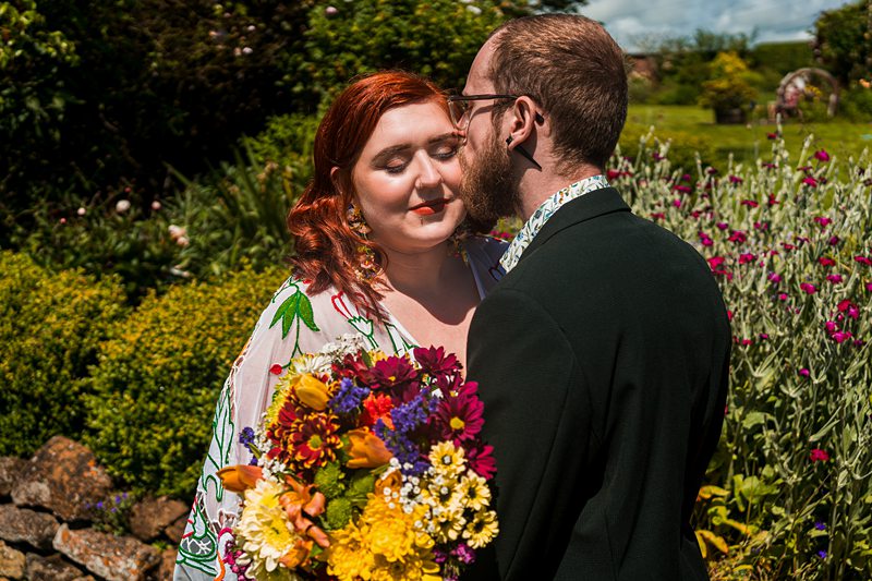Couple embracing in garden with bouquet of flowers.