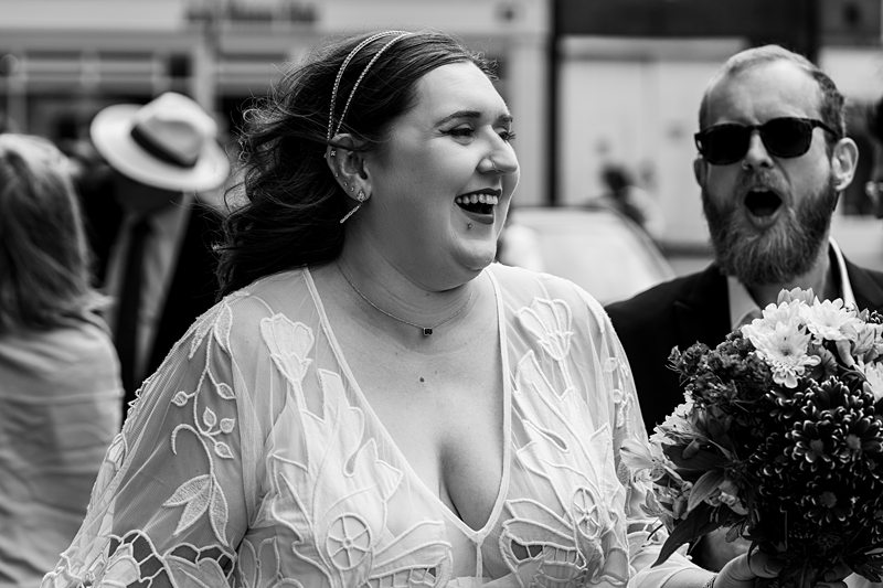 Bride and guest laughing at outdoor wedding.