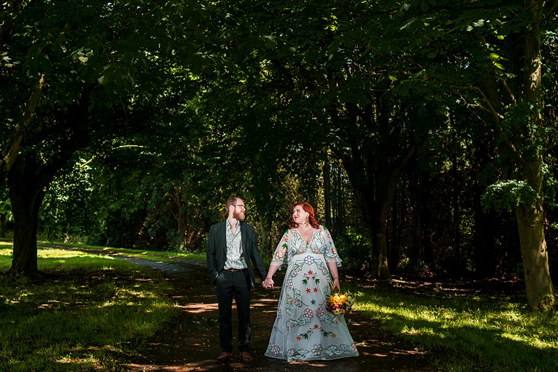 Couple walking in a forest holding hands.