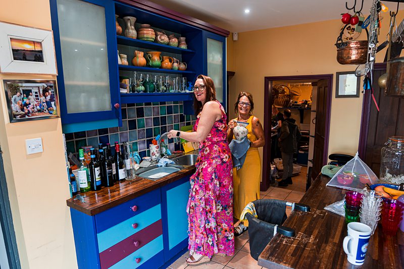 Two women smiling in colourful kitchen.