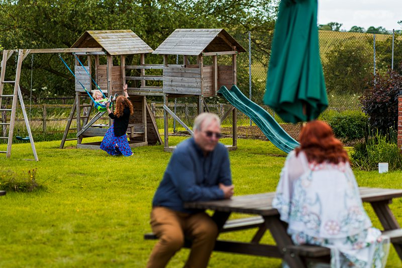 Adults and children in garden with play area.