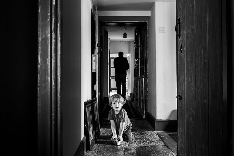 Child playing in hallway, adult in background.