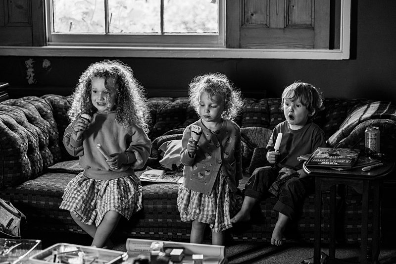 Children eating ice lollies on a sofa.